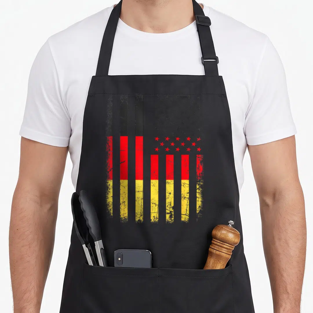 Germany american flag apron - Hybrid flag with black red yellow vertical stripes and distressed star field — shown on a black cotton canvas apron against a white background