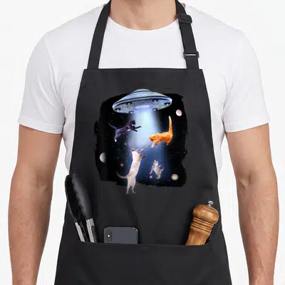 Kitty space cat apron - Four cats floating in a UFO beam with planets inside a rough black border — shown on a black cotton canvas apron against a white background