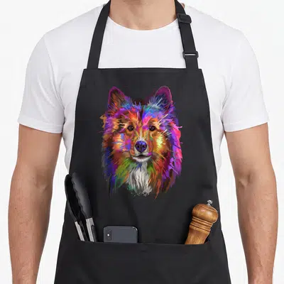 Shetland splash aprons - Multicolored watercolor Shetland Sheepdog head in blue red yellow green purple on black — shown on a black cotton canvas apron against a white background