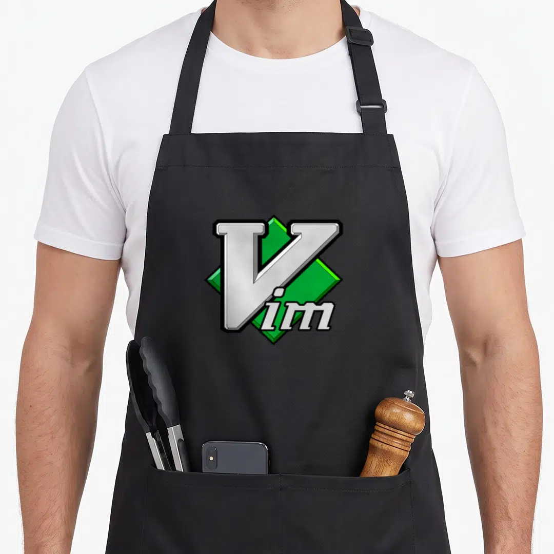 Script editor apron - Silver Vim text over a green diamond shape with black outlines — shown on a black cotton canvas apron against a white background