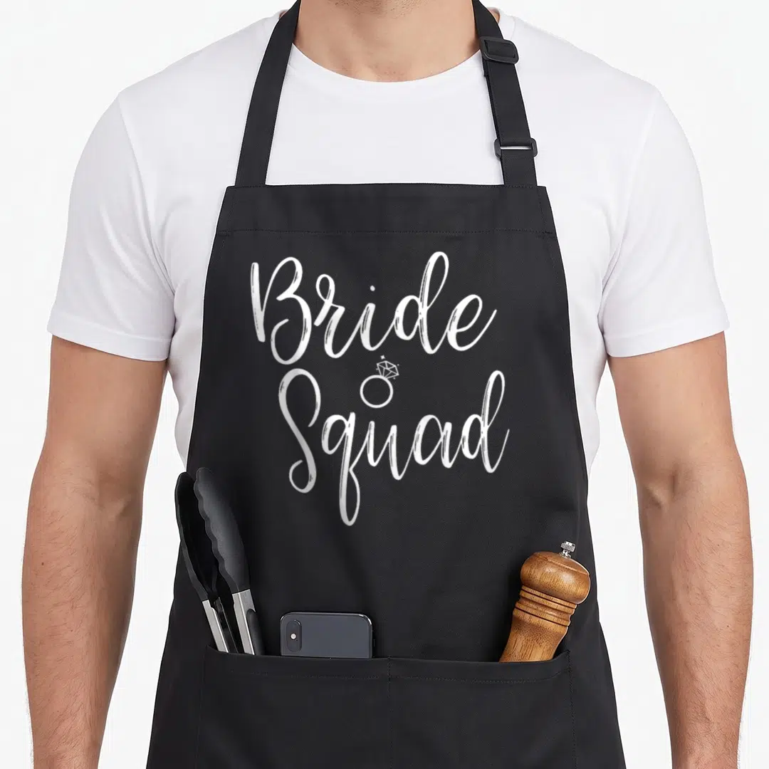 Squad bridal apron - White Bride Squad script text with small diamond ring icon between lines — shown on a black cotton canvas apron against a white background