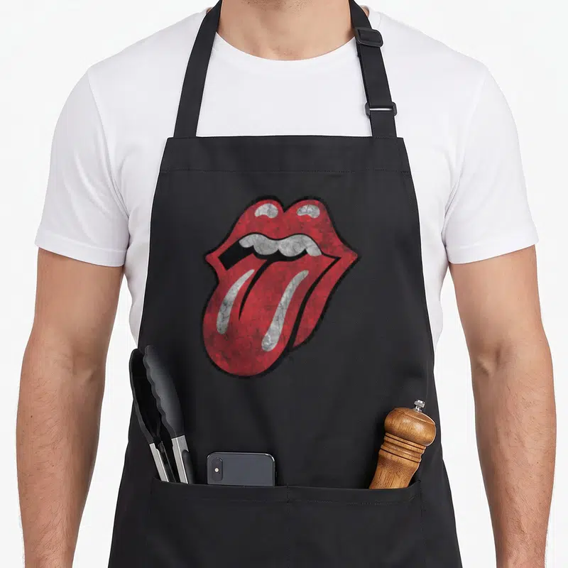 Cute distressed rolling stones apron - Red and white mouth with tongue sticking out on black background with distressed — shown on a black cotton canvas apron against a white background