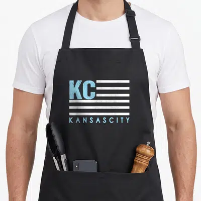 Flag kansas girl apron - Distressed KC text with white stripes and KANSAS CITY lettering in light blue — shown on a black cotton canvas apron against a white background