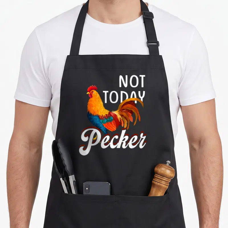 Today chicken apron - Cartoon rooster with NOT TODAY Pecker text in white red orange and blue — shown on a black cotton canvas apron against a white background