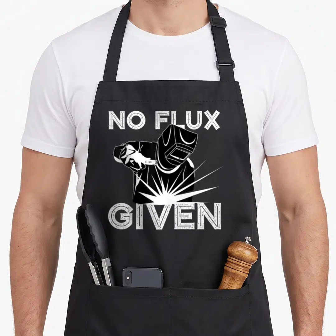 Welder arc apron - White NO FLUX GIVEN text surrounding a black welder holding a sparking torch — shown on a black cotton canvas apron against a white background
