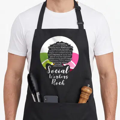 Queen magic apron - Grey female silhouette filled with white adjectives over colored circle with Social Workers Rock — shown on a black cotton canvas apron against a white background