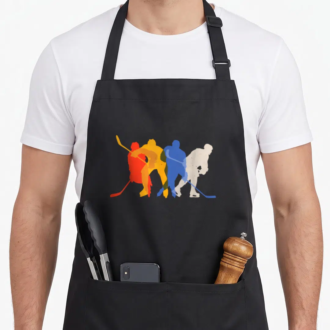 Ice hockey player apron - Four overlapping hockey player silhouettes in red, orange, blue, and white minimalist graphic — shown on a black cotton canvas apron against a white background