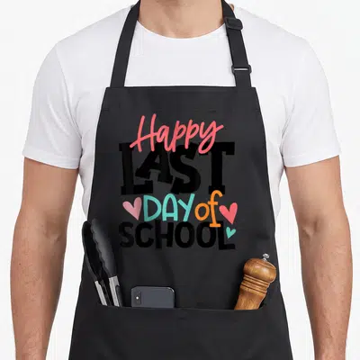 Graduation teacher apron - Stacked Happy LAST DAY of SCHOOL text in black pink teal orange with three small hearts — shown on a black cotton canvas apron against a white background