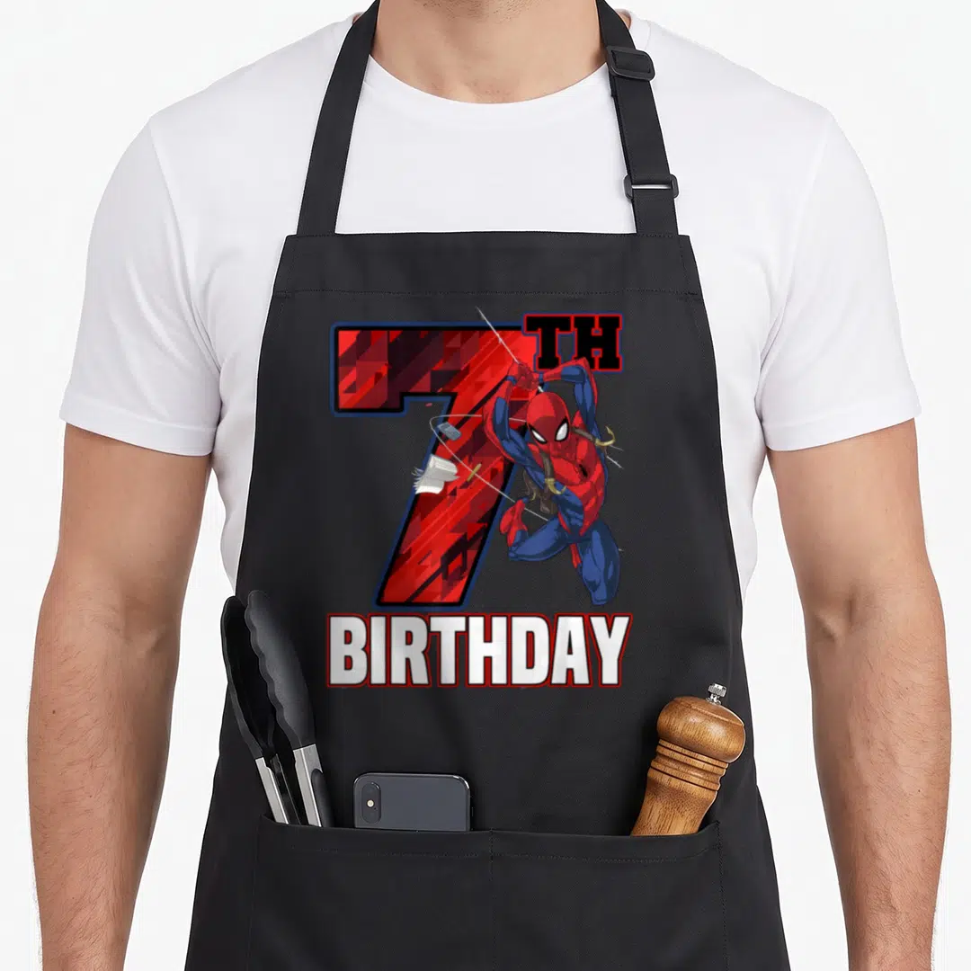 Web swing birthday apron - Spider-Man leaping in front of red 7TH BIRTHDAY text in cartoon style — shown on a black cotton canvas apron against a white background
