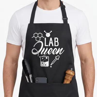 Queen laboratory apron - White Lab Queen text with molecule, beaker, and dropper graphics — shown on a black cotton canvas apron against a white background