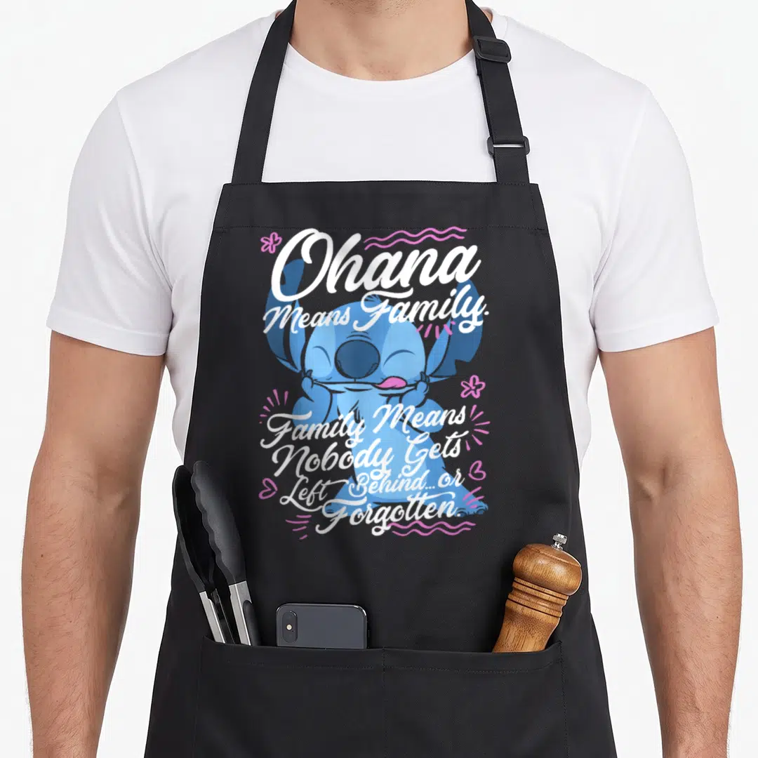 Ohana stitch apron - Blue cartoon character with Ohana means family text and pink floral accents — shown on a black cotton canvas apron against a white background