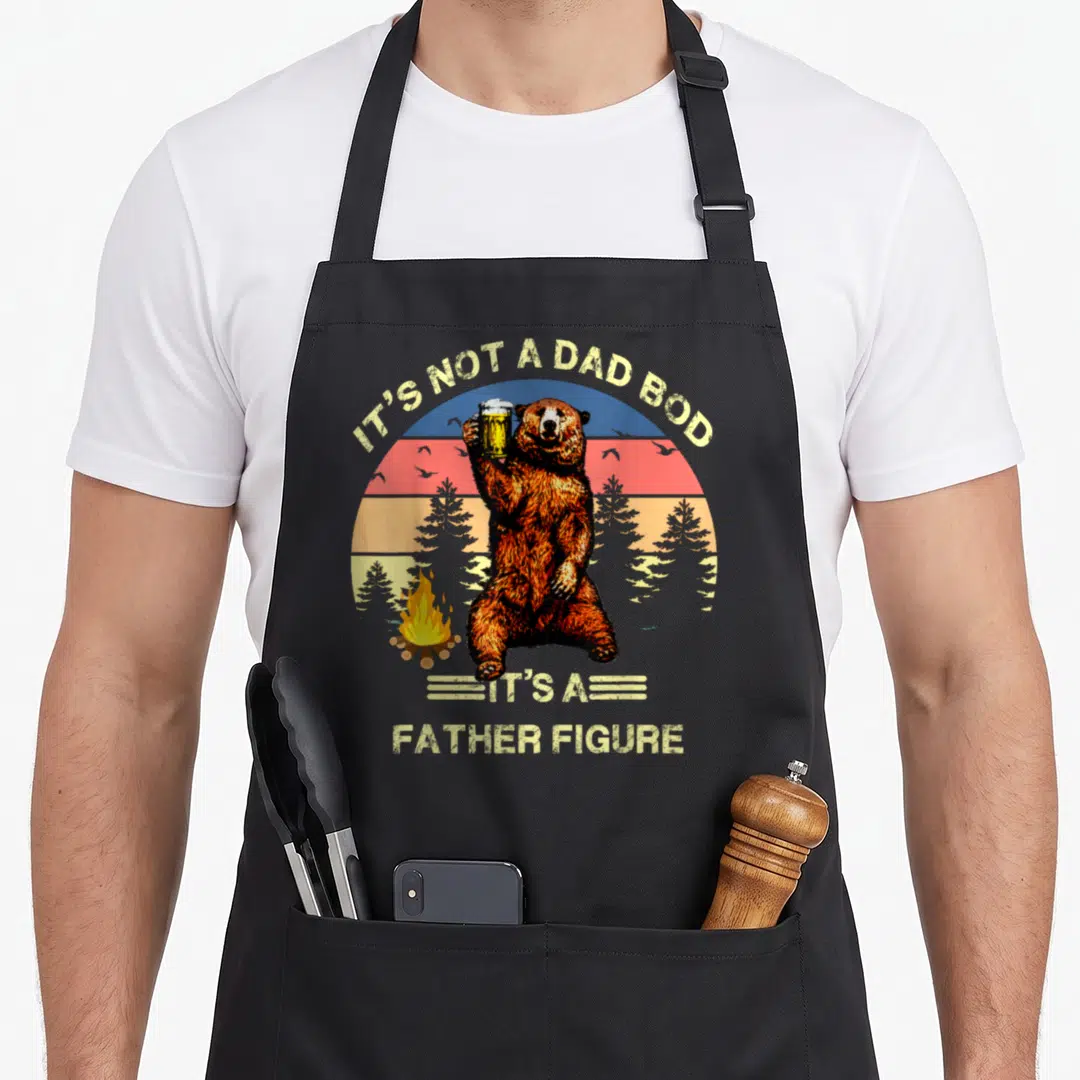Funny father dad bod apron - Retro bear holding beer mug with IT'S NOT A DAD BOD text — shown on a black cotton canvas apron against a white background