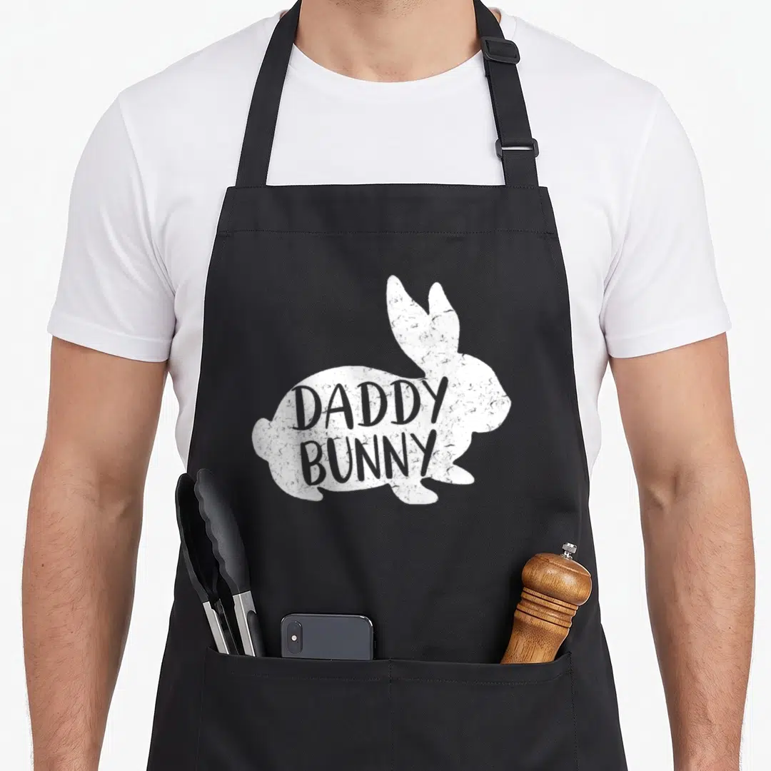 Daddy bunny apron - White distressed rabbit silhouette with grey DADDY BUNNY text stacked on body — shown on a black cotton canvas apron against a white background