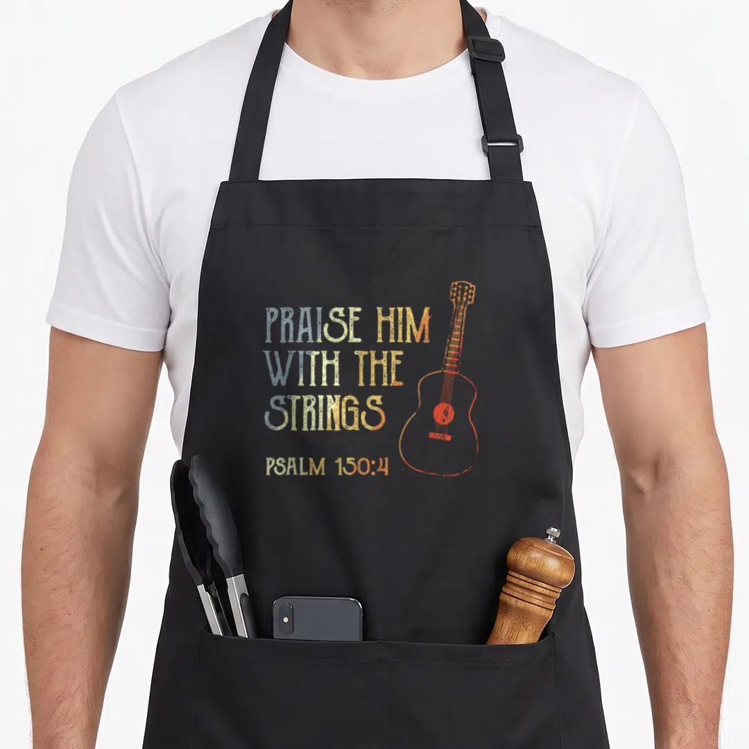 Guitarist bible verse apron - Distressed text Praise Him With The Strings Psalm 150:4 next to an orange guitar outline — shown on a black cotton canvas apron against a white background