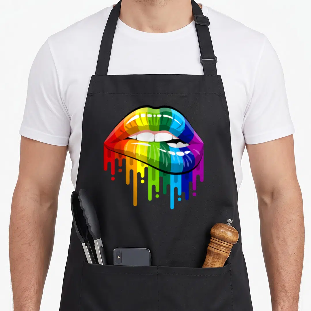 80s colorful apron - Rainbow colored lips with white teeth and dripping paint in red, orange, yellow, green, blue — shown on a black cotton canvas apron against a white background
