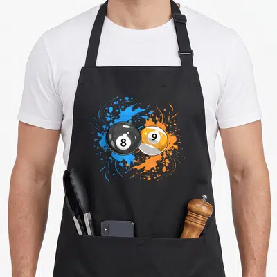 Funny ball billiards apron - Cartoon 8-ball and 9-ball overlapping over blue and orange paint splashes — shown on a black cotton canvas apron against a white background