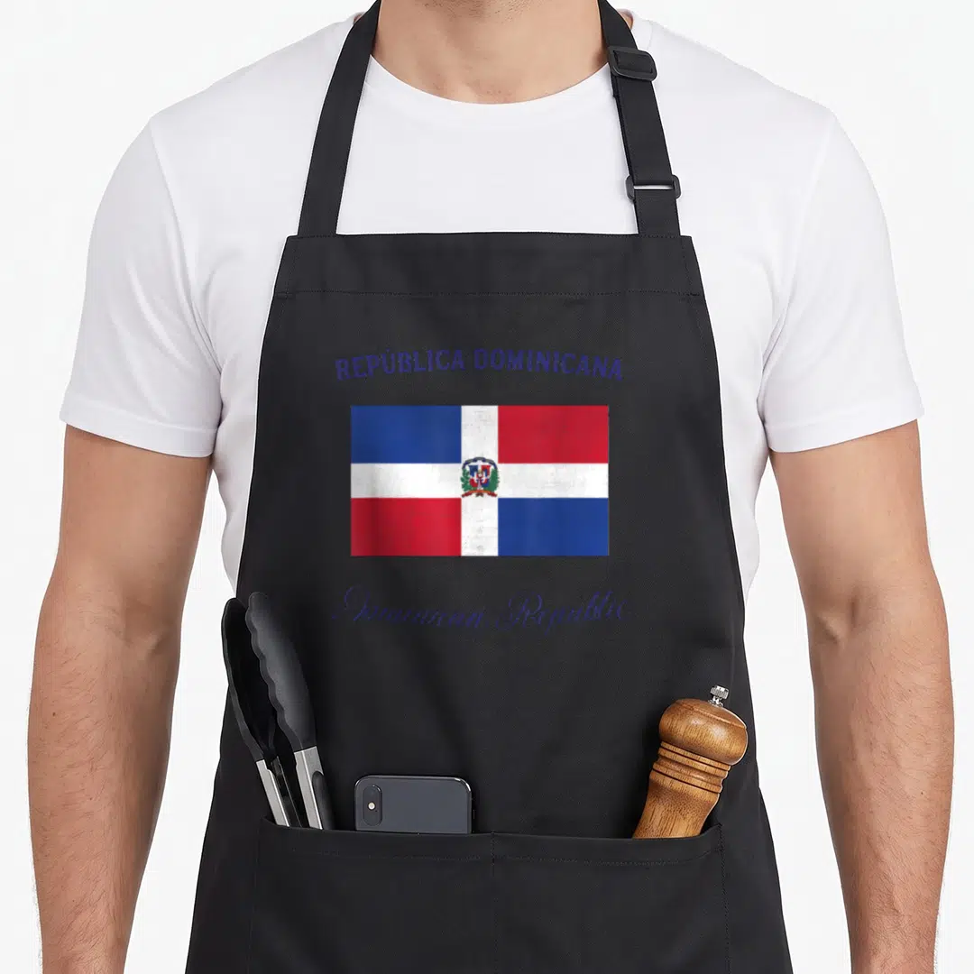 Flag dominican apron - Dominican Republic flag print with bilingual text in red white blue and purple — shown on a black cotton canvas apron against a white background