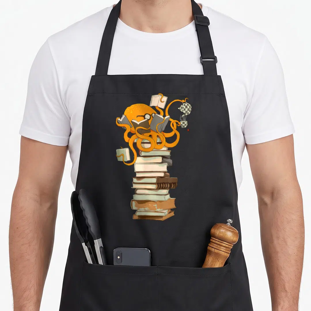 Reading coffee apron - Orange octopus perched on stacked books holding open pages and checkered tea set — shown on a black cotton canvas apron against a white background