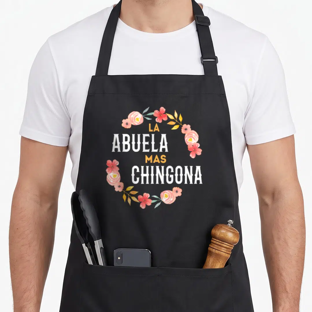 Abuela spanish aprons - La Abuela Mas Chingona text in white and yellow inside a pink and yellow watercolor floral — shown on a black cotton canvas apron against a white background