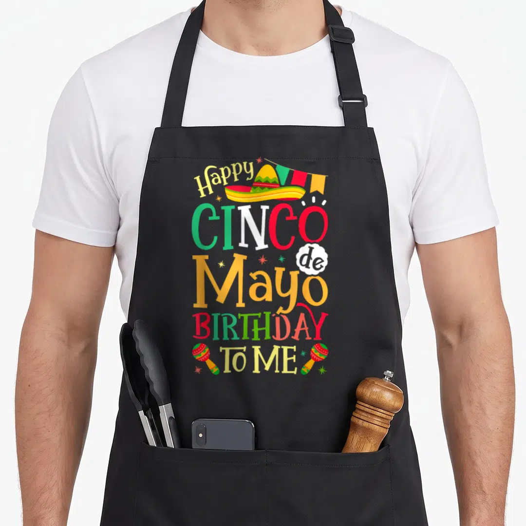 Birthday mexican apron - Happy CINCO de Mayo BIRTHDAY TO ME text with sombrero, bunting, and two maracas — shown on a black cotton canvas apron against a white background