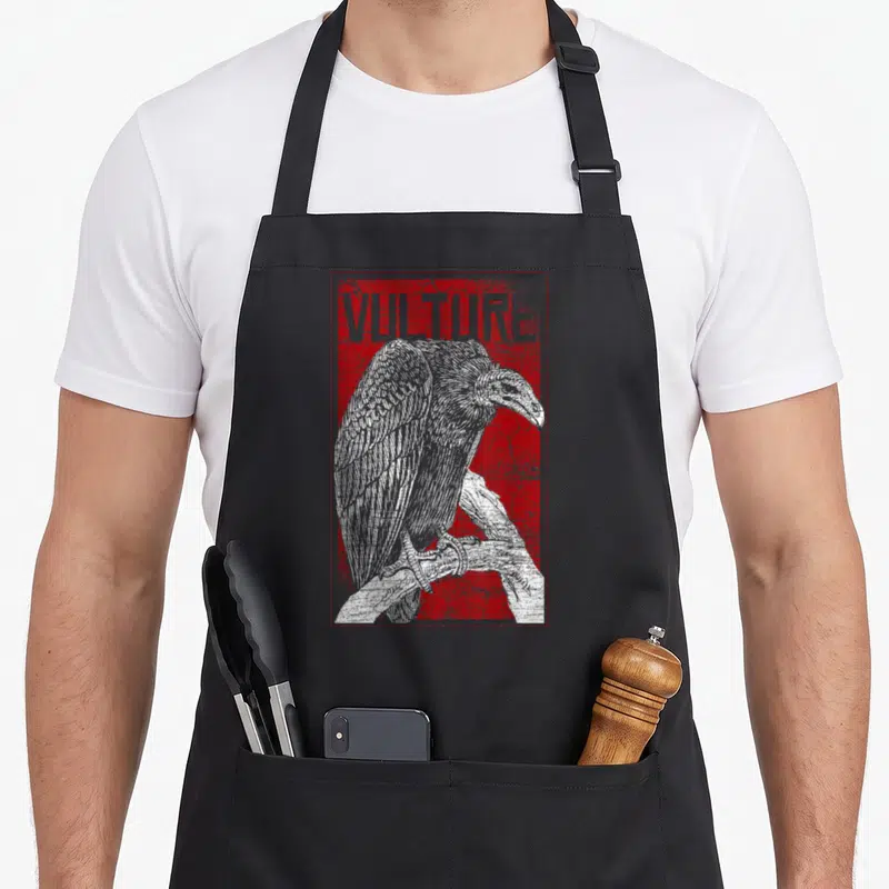 Africa bird apron - VULTURE text above perched white bird on distressed red background — shown on a black cotton canvas apron against a white background