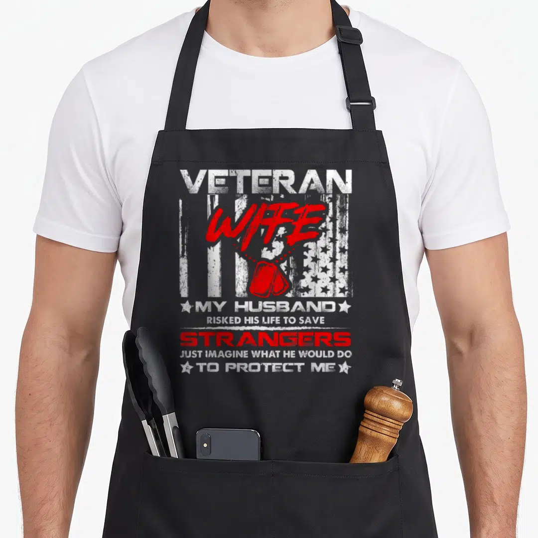 Wife military best husband apron - Distressed white and red text with dog tags and USA flag reading VETERAN WIFE MY — shown on a black cotton canvas apron against a white background