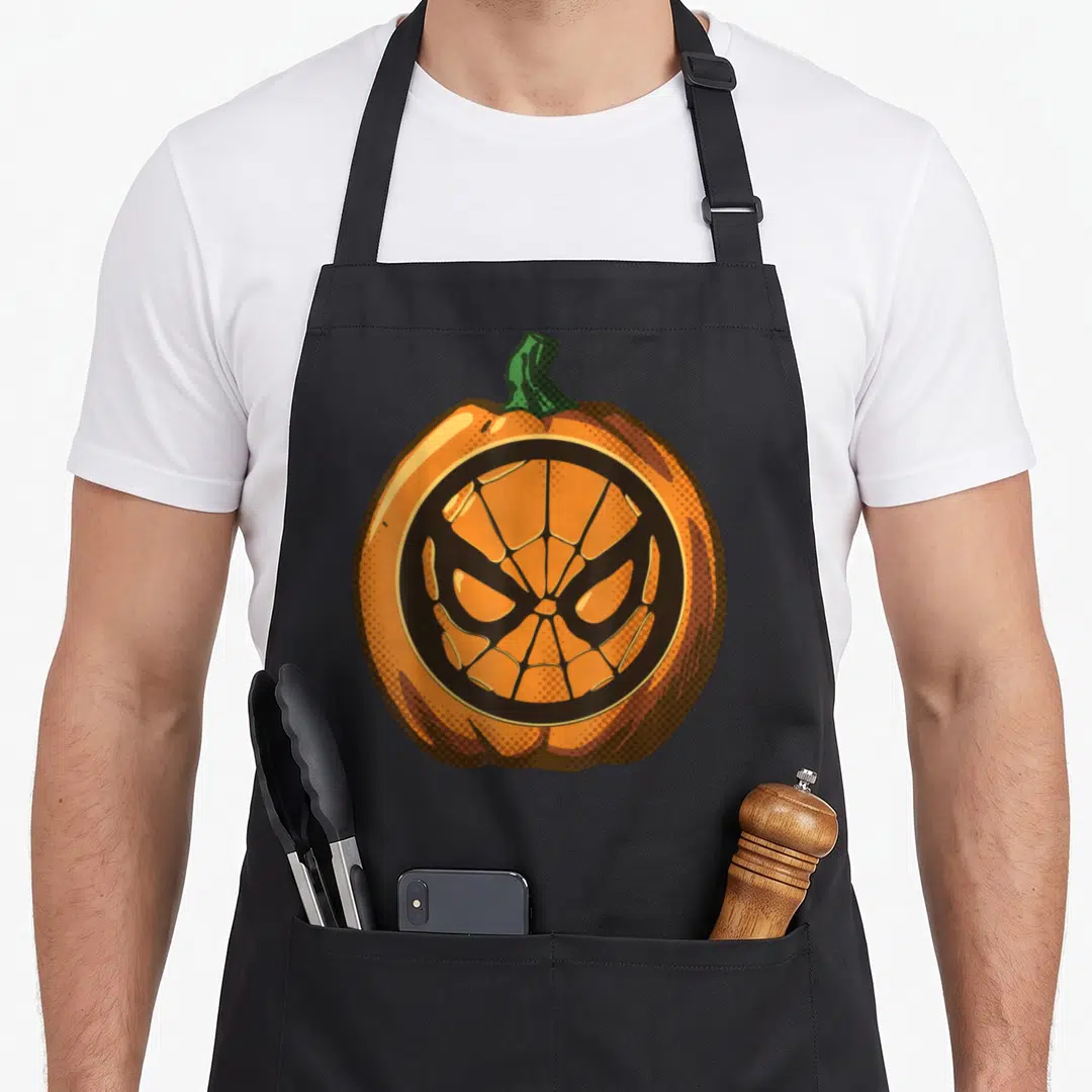 Cute pumpkin halloween kitchen aprons - Orange pumpkin with black spider-man mask carving and green stem in cartoon — shown on a black cotton canvas apron against a white background