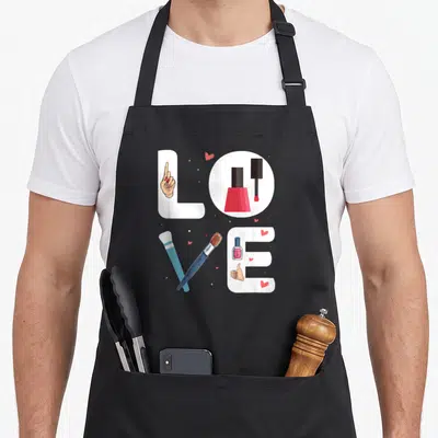 Nail technician manicurist apron - LOVE text formed by nail tools and hands with small red hearts — shown on a black cotton canvas apron against a white background