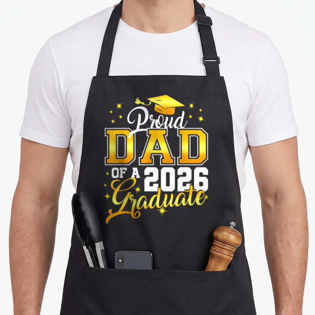 Graduation proud dad apron - Gold and white Proud DAD OF A 2026 Graduate text with cap and stars — shown on a black cotton canvas apron against a white background