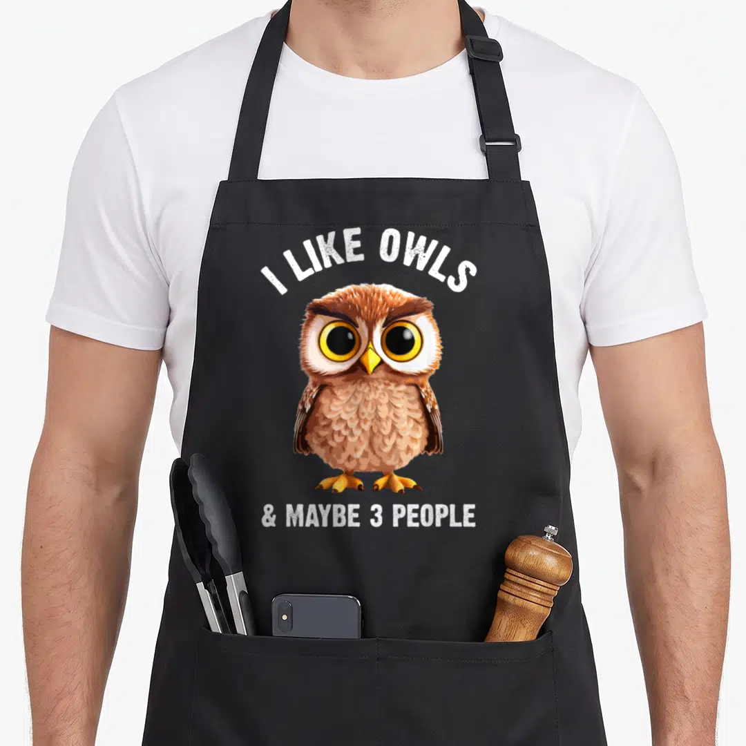 Zookeeper bird apron - Cartoon owl with I Like Owls & Maybe 3 People text in brown white and yellow — shown on a black cotton canvas apron against a white background