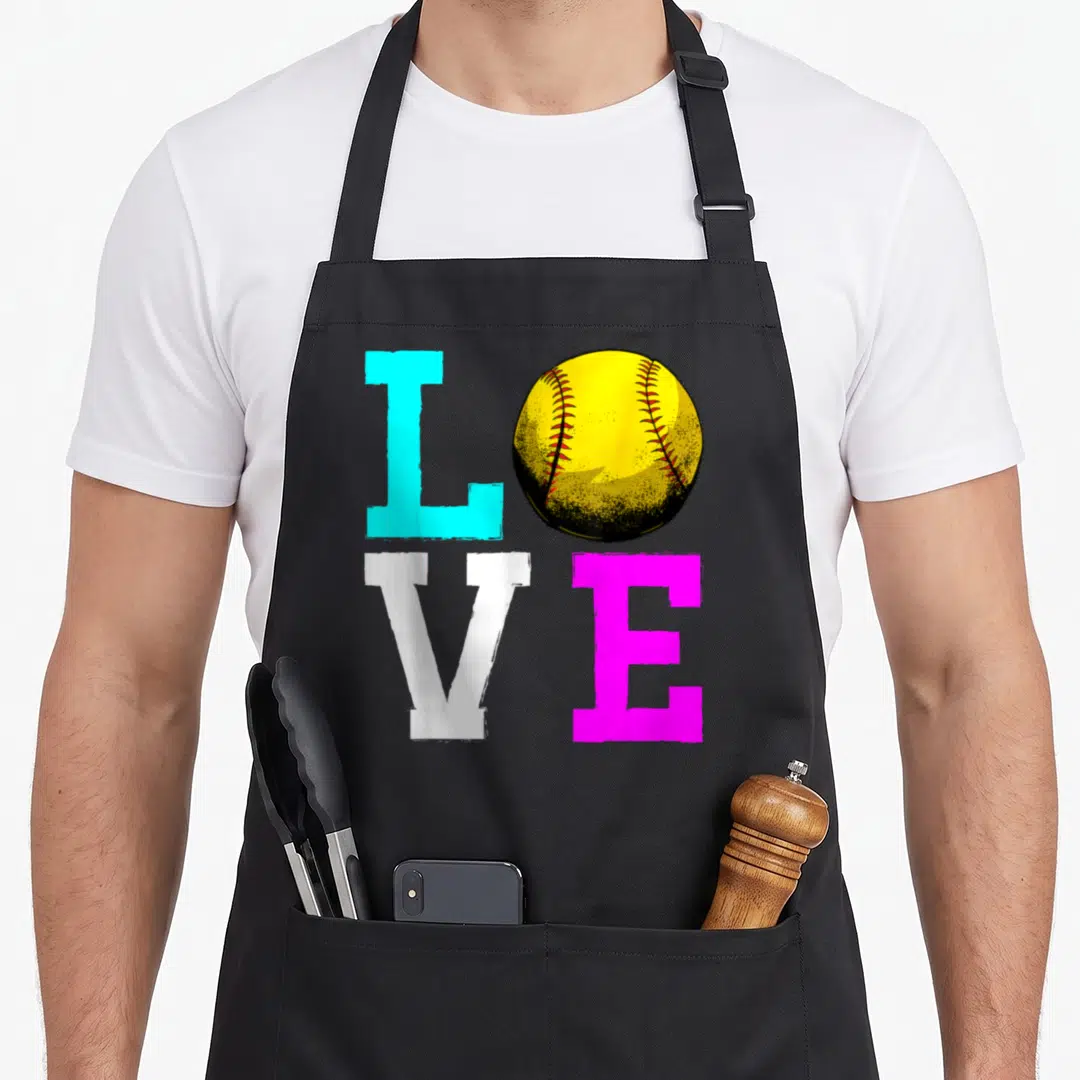Coach i love softball apron - Colorful LOVE text with yellow softball replacing O in cyan white magenta — shown on a black cotton canvas apron against a white background