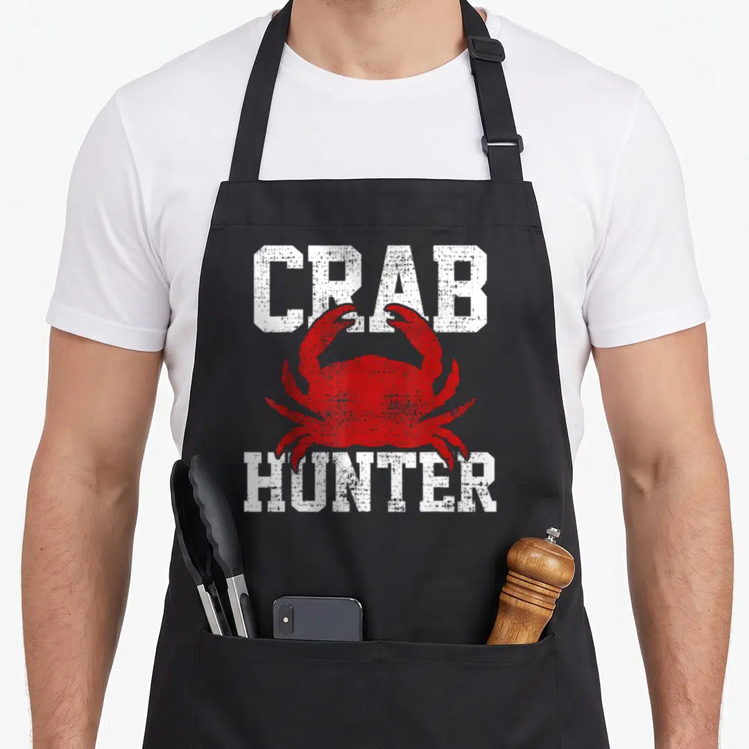 Funny crab apron - CRAB HUNTER text surrounding a red crab silhouette — shown on a black cotton canvas apron against a white background