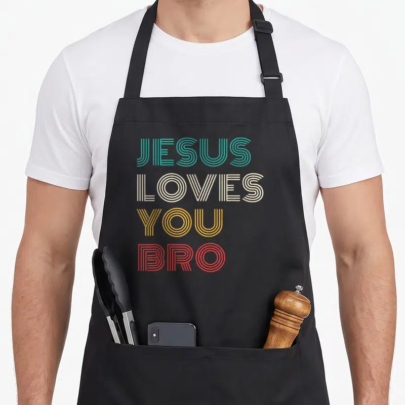 Bro christian aprons - Stacked retro text reading JESUS LOVES YOU BRO in teal beige yellow and red lines — shown on a black cotton canvas apron against a white background