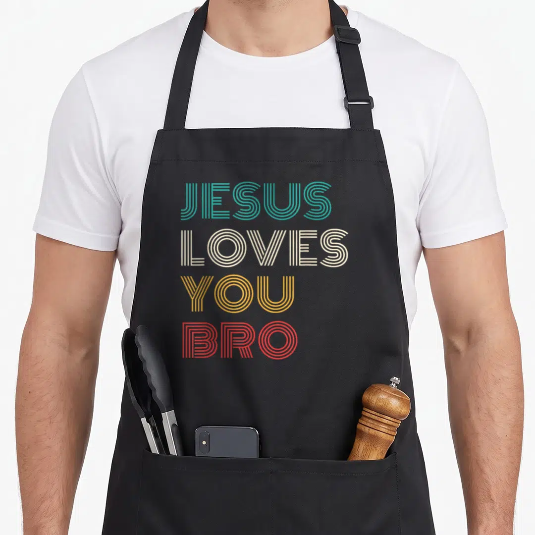 Bro christian aprons - Stacked retro text reading JESUS LOVES YOU BRO in teal beige yellow and red lines — shown on a black cotton canvas apron against a white background