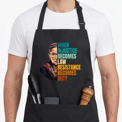 Injustice criminal justice apron - Portrait of woman beside stacked text WHEN INJUSTICE BECOMES LAW RESISTANCE BECOMES — shown on a black cotton canvas apron against a white background