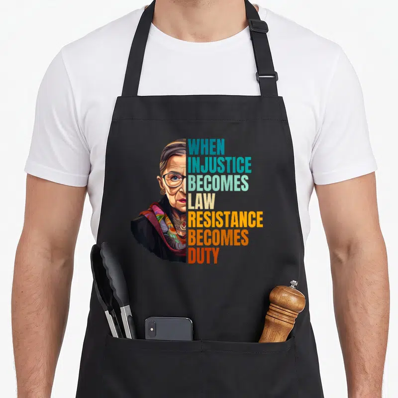 Injustice criminal justice apron - Portrait of woman beside stacked text WHEN INJUSTICE BECOMES LAW RESISTANCE BECOMES — shown on a black cotton canvas apron against a white background