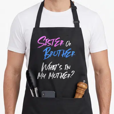 Sibling apron or apron - Sister Or Brother What's In My Mother text in pink blue white brush font — shown on a black cotton canvas apron against a white background