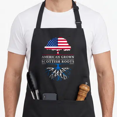 Scottish scotland apron - Tree with US flag canopy and Scottish saltire roots split by American Grown with Scottish — shown on a black cotton canvas apron against a white background