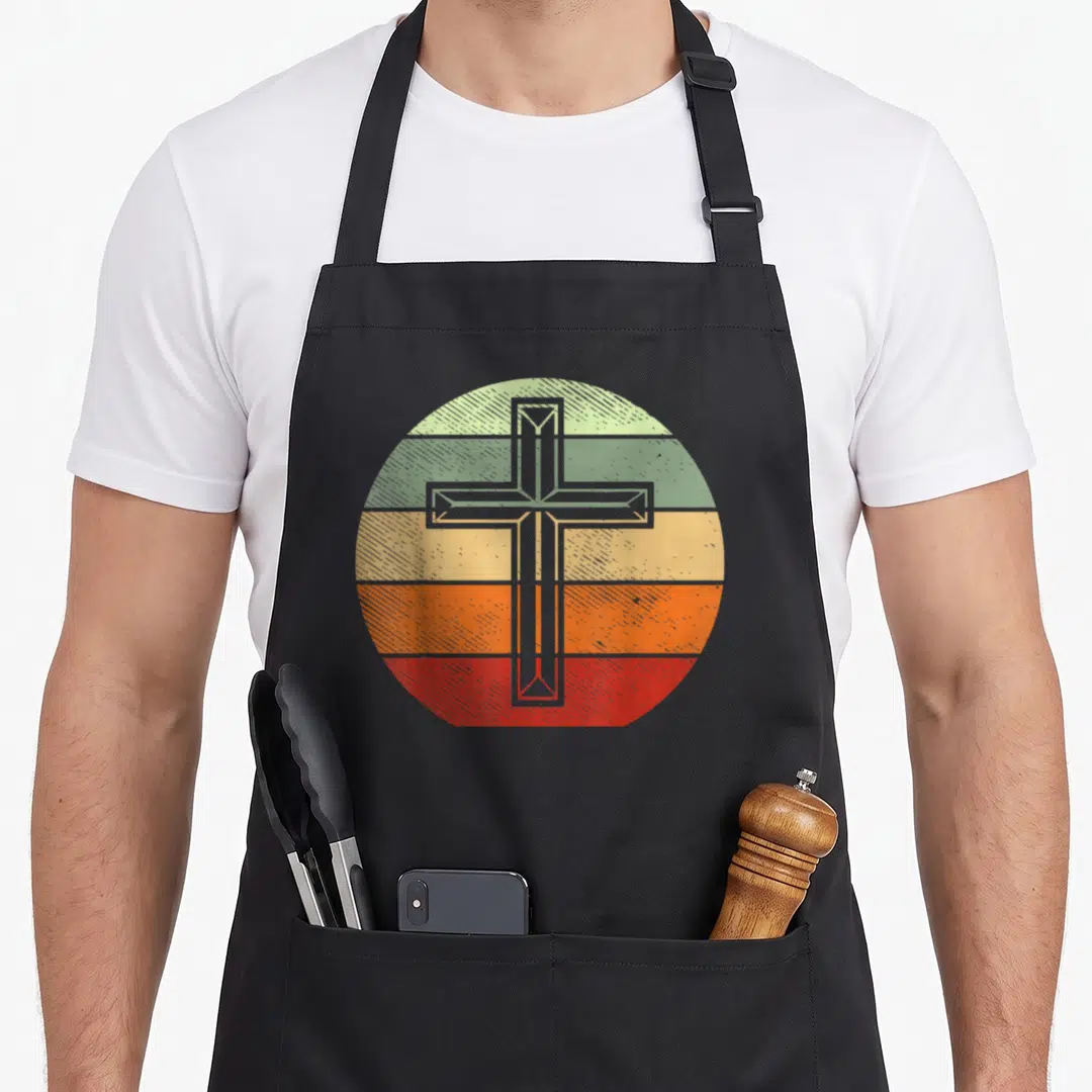 Christ god cross apron - Retro grey cross over five horizontal stripes in green yellow orange and red — shown on a black cotton canvas apron against a white background