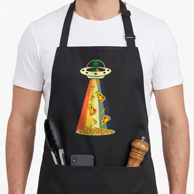 Ufo pizza apron - Green alien in beige UFO dropping multi-colored pizza slices through a rainbow striped beam — shown on a black cotton canvas apron against a white background