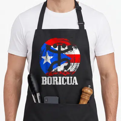 Taino pride apron - Distressed Puerto Rican flag circle with grey silhouette, palm trees, and BORICUA text — shown on a black cotton canvas apron against a white background