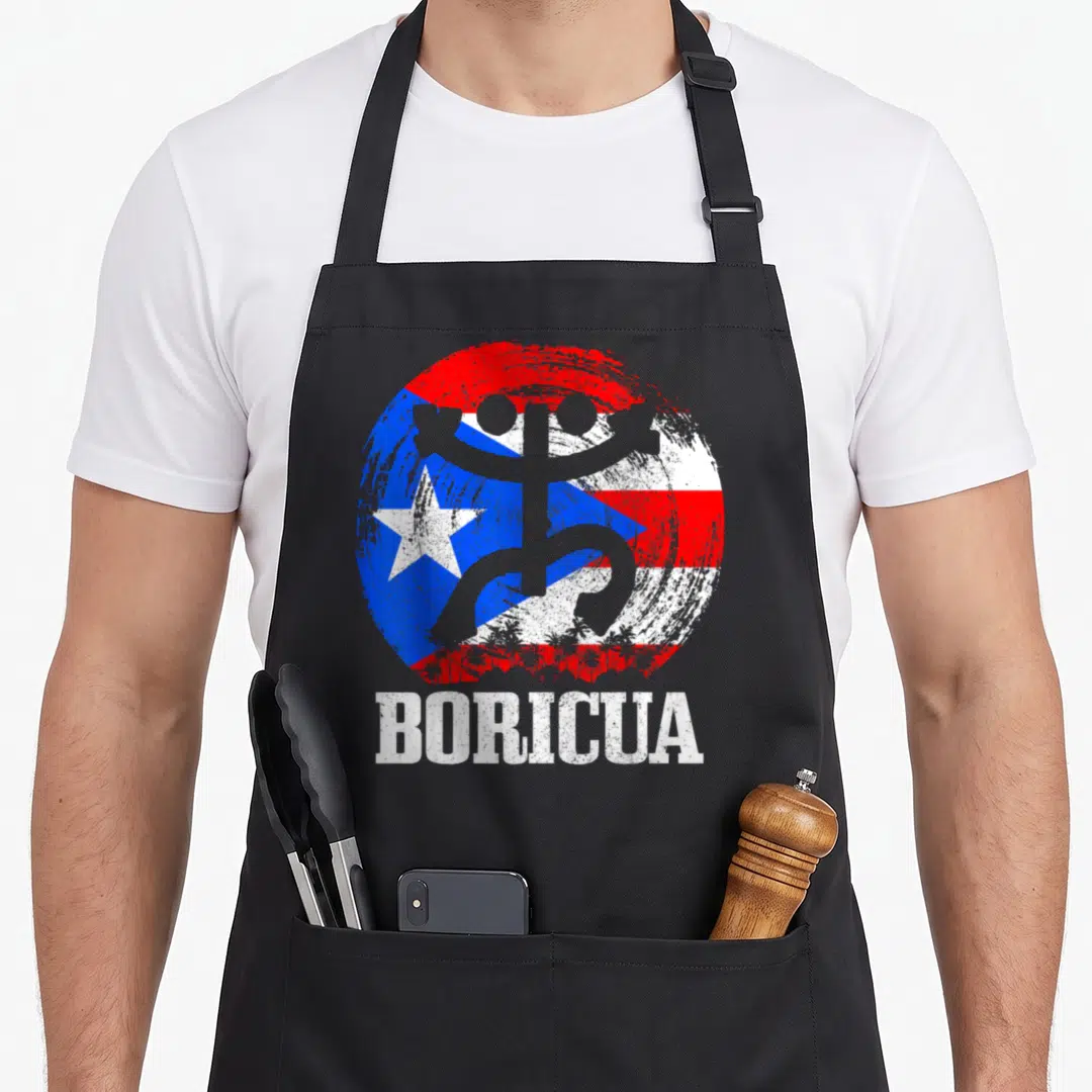 Taino pride apron - Distressed Puerto Rican flag circle with grey silhouette, palm trees, and BORICUA text — shown on a black cotton canvas apron against a white background