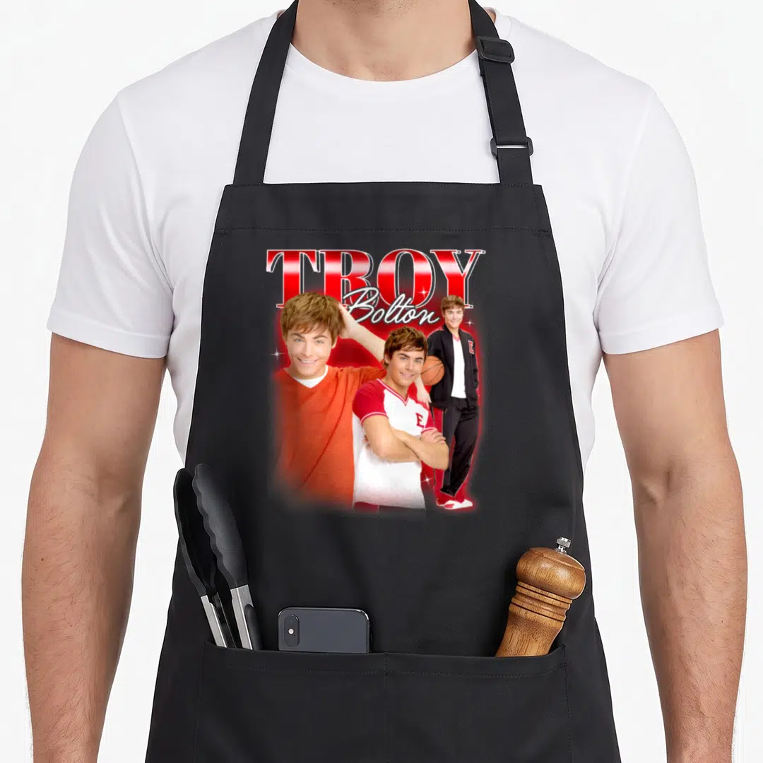 Musical school apron - Troy Bolton text with three layered photo portraits in red and orange — shown on a black cotton canvas apron against a white background