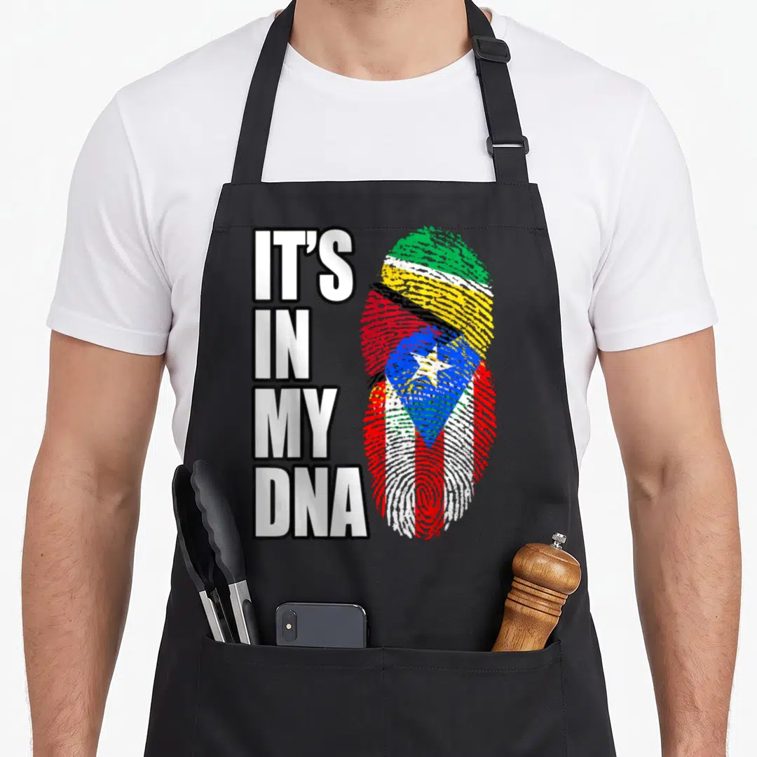 Guyanese heritage aprons - IT'S IN MY DNA text beside a fingerprint shaped like a Guyana and Puerto Rico flag composite — shown on a black cotton canvas apron against a white background