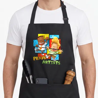 Captain prank apron - Two cartoon boys amidst orange green yellow blue red squares with PRANK ARTISTS text below — shown on a black cotton canvas apron against a white background