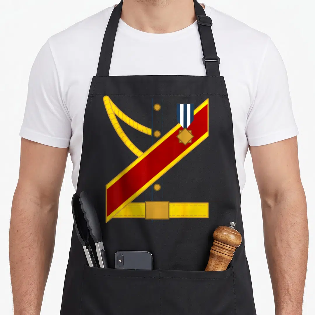 Halloween prince charming apron - Minimalist military uniform with red sash, yellow aiguillette, medal, and blue button — shown on a black cotton canvas apron against a white background