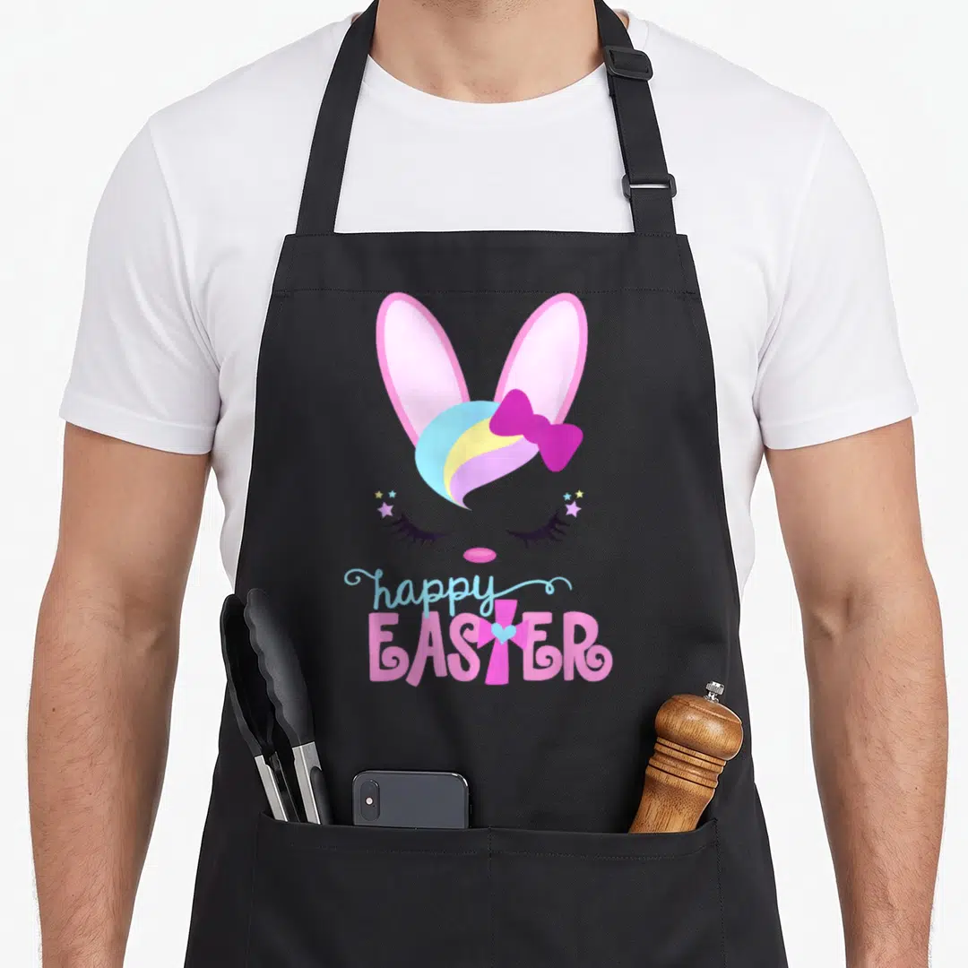 Bunny christian easter apron - Sleeping bunny face with rainbow mane and happy EASTER text where T is a cross — shown on a black cotton canvas apron against a white background