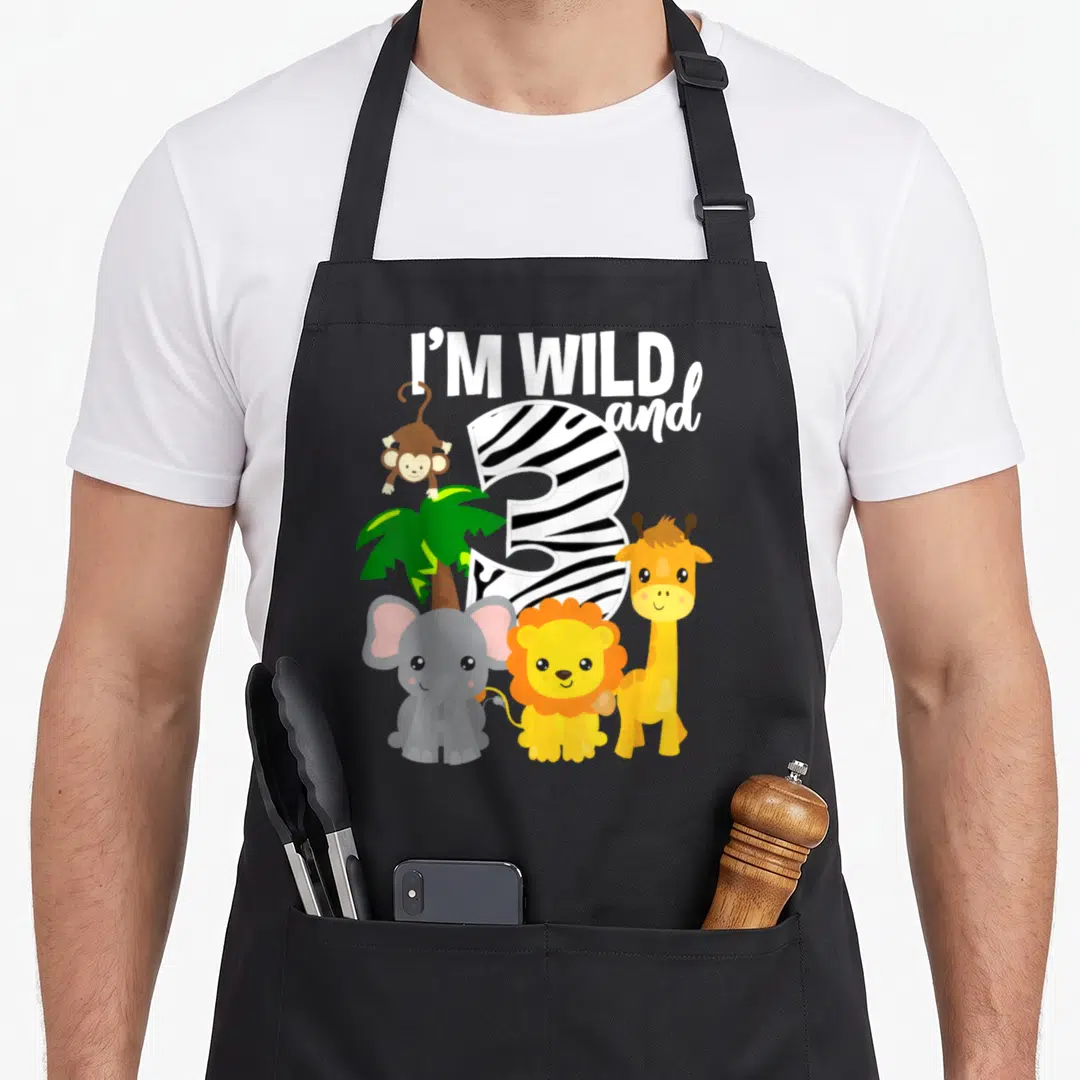 Zoo theme safari birthday apron - Zebra-striped number 3 with elephant lion giraffe monkey and palm tree under I'M WILD — shown on a black cotton canvas apron against a white background