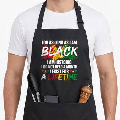 History a's aprons - Stacked white text reading For As Long As I Am Black over red yellow and green scribbles — shown on a black cotton canvas apron against a white background