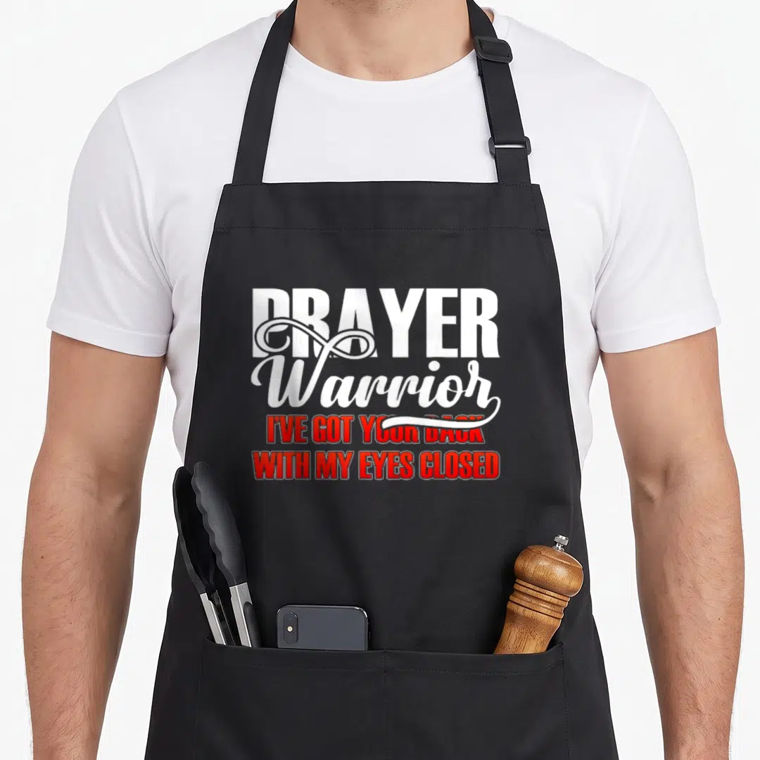 Bible prayer apron - Stacked white and red text reading Prayer Warrior I've Got Your Back With My Eyes Closed — shown on a black cotton canvas apron against a white background